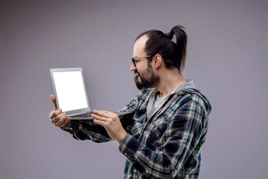 Concerned computer technician troubleshoots a laptop with a blank screen, showing worry and frustration in a gray studio