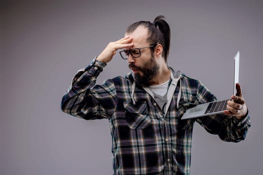 Technician is holding a laptop and regretting checking it because it has a security problem. He is feeling disappointed about what he saw