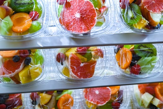 Plastic boxes with pre-packaged fruit salads, put up for sale in a commercial refrigerator