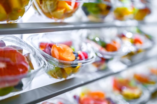 Plastic boxes with pre-packaged fruit salads, put up for sale in a commercial refrigerator