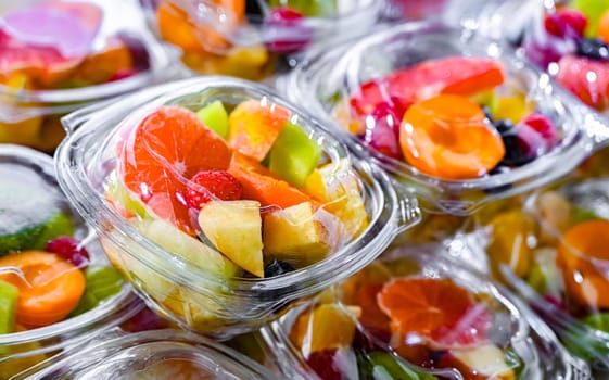 Plastic boxes with pre-packaged fruit salads, put up for sale in a commercial refrigerator