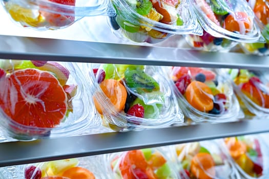 Plastic boxes with pre-packaged fruit salads, put up for sale in a commercial refrigerator