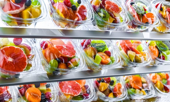 Plastic boxes with pre-packaged fruit salads, put up for sale in a commercial refrigerator