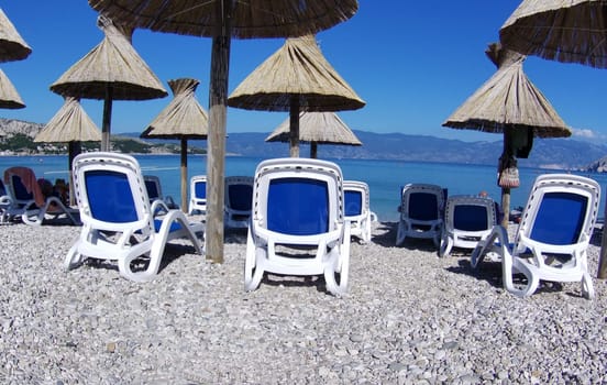 Prices have risen after the introduction of the euro in Croatia - many beach chairs under the teepee umbrellas are still empty at the beginning of the season - beach scene in Baska/island of Krk  Theme picture Croatia / Hrvatska / Croatia 2024