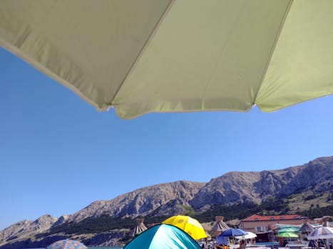 Beach scene in Baska/island Krk - umbrella,mountains,sea  Theme picture Croatia / Hrvatska / Croatia 2024