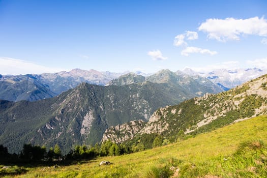 Panorama of Italian Alps with blue sky and clouds. Calm landscape, tranquil scenic view.