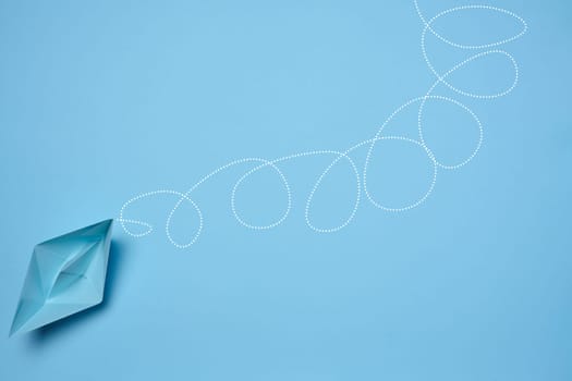 Blue paper boat and a long tangled path, symbolizing the concept of a challenging journey, top view