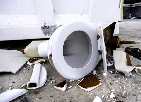 Detail of broken and damaged ceramic toilet lying on the street