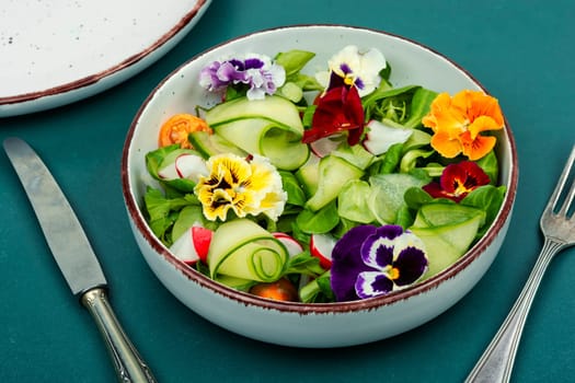 Fresh green salad of vegetables, edible flowers, field pansies, violets. Detox food