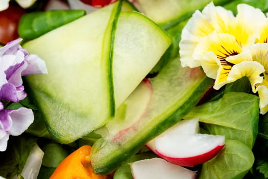 Fresh green salad of vegetables, edible flowers, field pansies, violets. Detox food