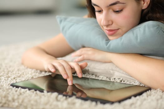 Serious woman using tablet on a carpet at home