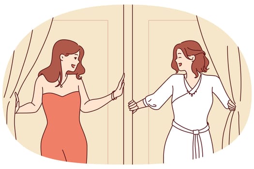 Two women leave fitting room in elegant evening dresses for gala dinner or party. Attractive girls in beautiful dresses are standing near fitting room of fashionable clothes store for festive ball