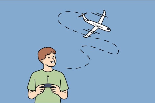 Little boy uses radio-controlled airplane and smiles, rejoicing at appearance of new toy. Happy boy with remote control for playing with aircraft, dreams of becoming pilot when grows up