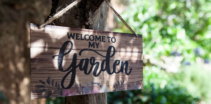 Garden welcome sign with mediterranean courtyard as background. English language letters