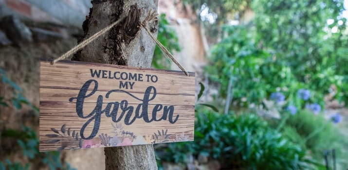 Garden welcome sign with mediterranean courtyard as background. English language letters