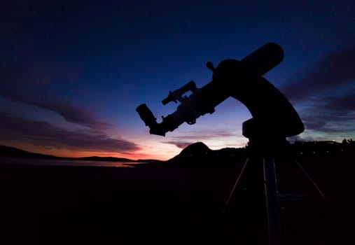 Telescope at sunset with Alange Castle as  background. Astrotourism activities in Extremadura, Spain