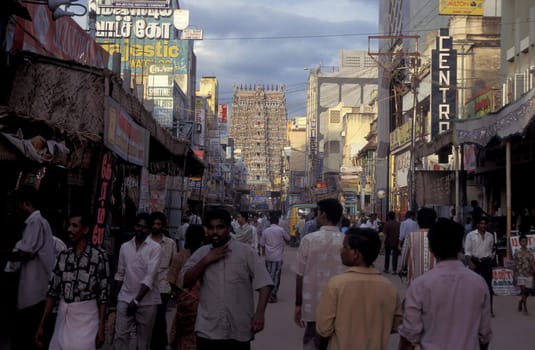 People in a street with a view of the Tower of the Meenakshi Amman Temple in the city of Madurai in the Province Tamil Nadu in India.  India, Madurai, April, 1998