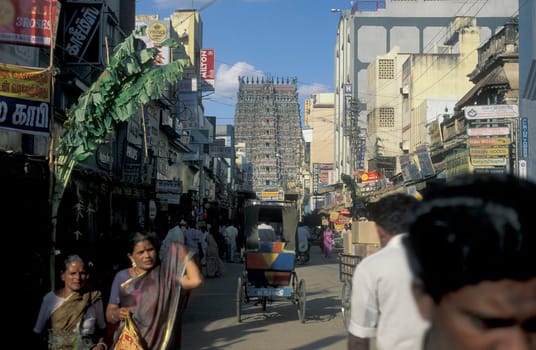 People in a street with a view of the Tower of the Meenakshi Amman Temple in the city of Madurai in the Province Tamil Nadu in India.  India, Madurai, April, 1998