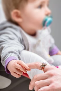 Sweet baby girl holds her mother's finger on a stroller, radiating love and tenderness. The bond between them showcases family beauty and childhood innocence, nurturing a strong connection