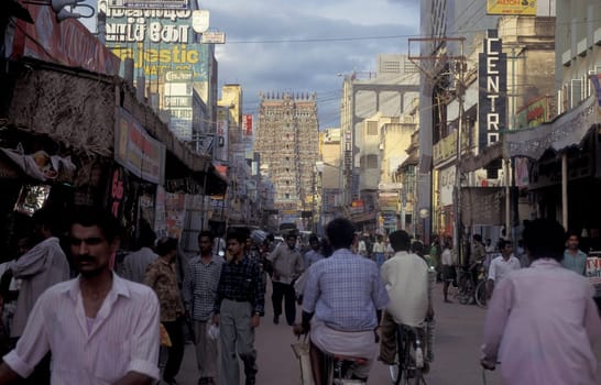 People in a street with a view of the Tower of the Meenakshi Amman Temple in the city of Madurai in the Province Tamil Nadu in India.  India, Madurai, April, 1998