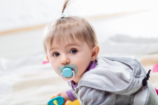 Happy baby girl crawls on a blanket, surrounded by toys, radiating innocence and joy. Her expression shows wonder and curiosity, symbolizing family love