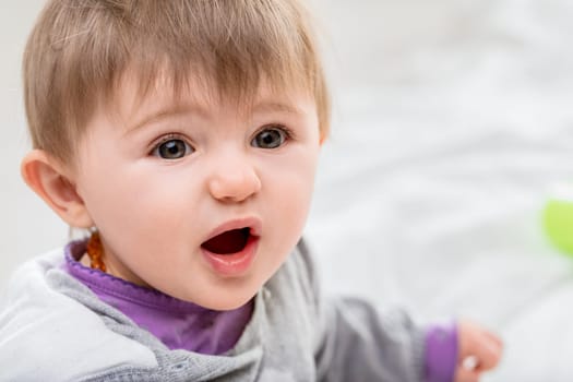 Surprised baby girl in a close up portrait, looking up with wide eyes and a sense of wonder, embodying curiosity and happiness in cute baby clothes