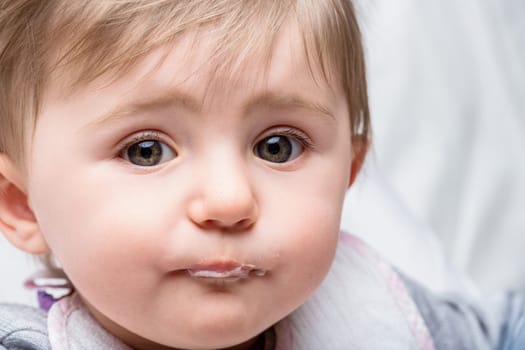 Sweet baby girl with drool on her chin makes a funny face, capturing childhood innocence and joy
