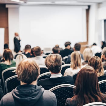 Speaker giving a talk in conference hall at business event. Rear view of unrecognizable people in audience at the conference hall. Business and entrepreneurship concept