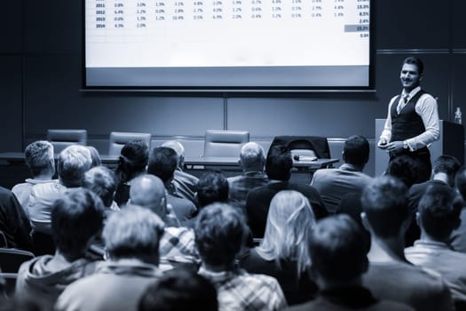 Speaker Giving a Talk at Business Meeting. Audience in the conference hall. Business and Entrepreneurship concept. Black and white blue toned image.