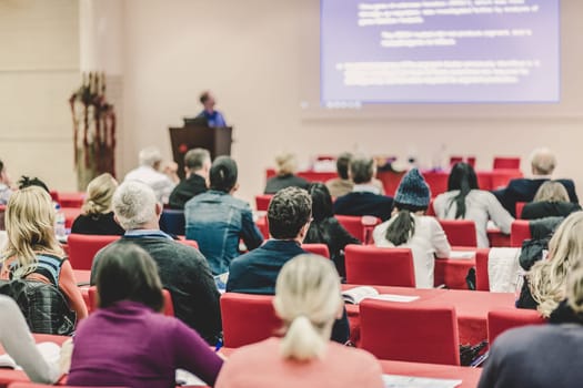 Speaker Giving a Talk at Business Meeting. Audience in the conference hall. Business and Entrepreneurship. Focus on unrecognizable people from rear.