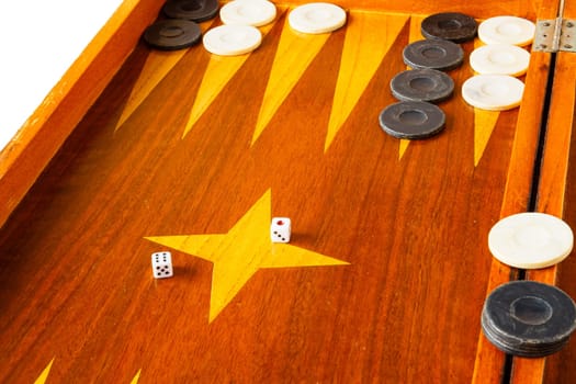 Old varnished wooden board game with plastic checkers and dice. Selective focus with shallow depth of field.