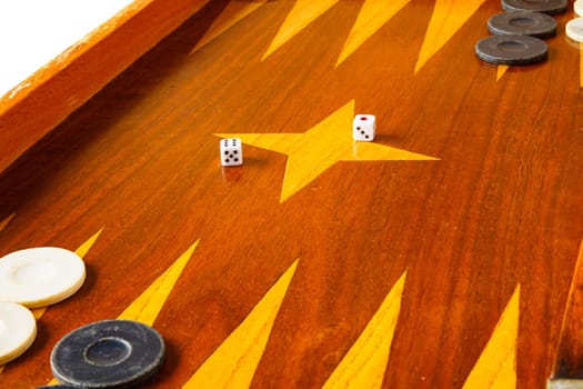 Old varnished wooden board game with plastic checkers and dice. Selective focus with shallow depth of field.