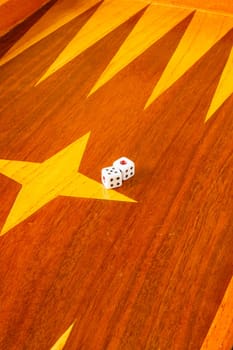 Old varnished wooden board game with plastic checkers and dice. Selective focus with shallow depth of field.