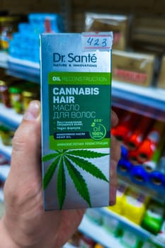 Sokuluk, Kyrgyzstan - April 5, 2024: hand holding box of cannabis hair hemp oil in a small grocery store