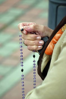 Hands of a woman holding a rosary while praying, Christian daily devotional of a worshiper of God the Savior, Basilica of Assumption of the Virgin Mary in Marija Bistrica, Croatia