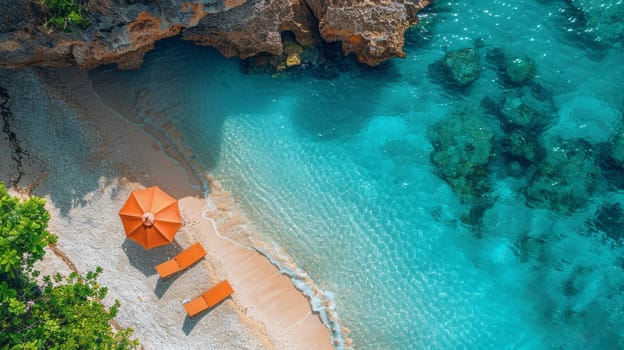 Aerial view of a secluded beach with an orange umbrella and lounge chairs beside turquoise waters and rocky cliffs.
