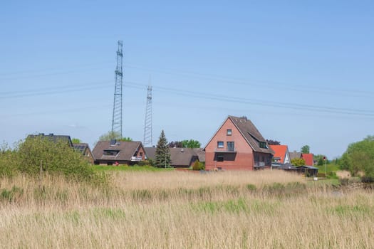 Brick residential building with electricity pylons on the River Este, Buxtehude, Lower Saxony, Germany