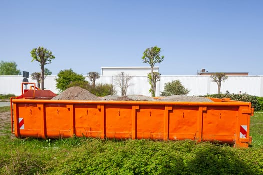 Container, orange skip for building rubble standing on a meadow, Germany