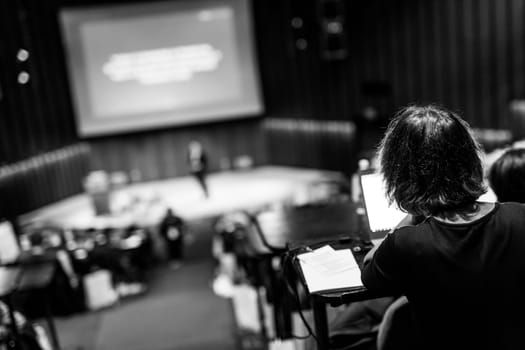 Conference and Presentation. Audience at the conference hall. Business and Entrepreneurship. Faculty lecture and workshop. Focus on unrecognizable person in audience making notes on laptop.