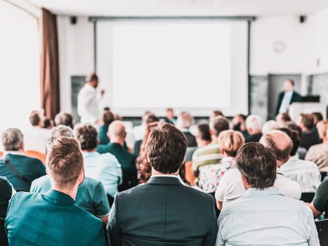 I have a question. Group of business people sitting at the chairs in conference hall. Businessman standing up asking a question. Conference and Presentation. Business and Entrepreneurship.