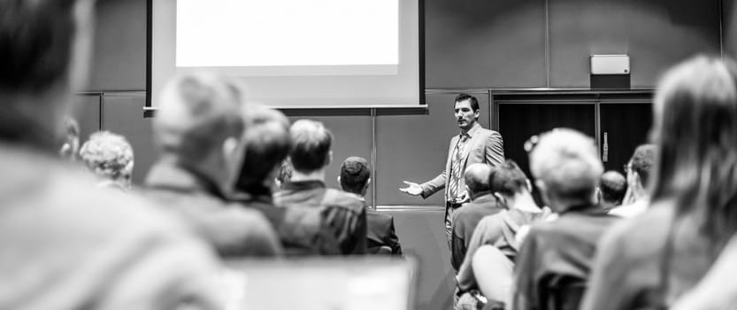 Speaker giving a talk in conference hall at business meeting event. Rear view of unrecognizable people in audience at the conference hall. Business and entrepreneurship concept.