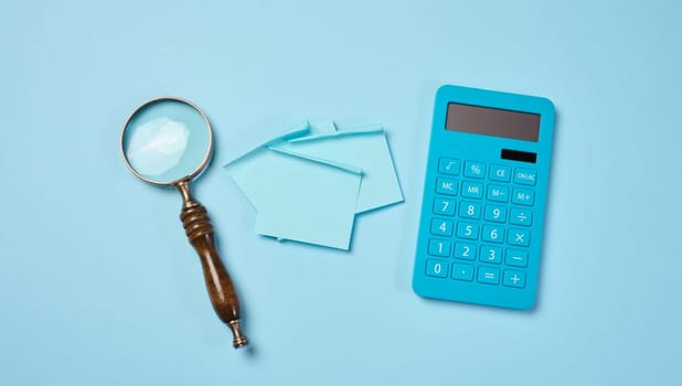 Magnifier and calculator on a blue background, budget calculation. View from above