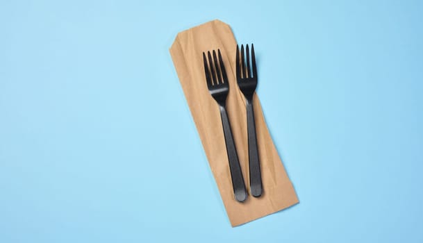Plastic black forks on a blue background, disposable picnic items, top view
