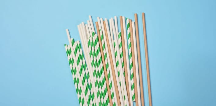 Disposable paper straws on a blue background, top view