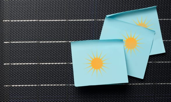 Paper stickers glued on black solar panel, renewable energy concept