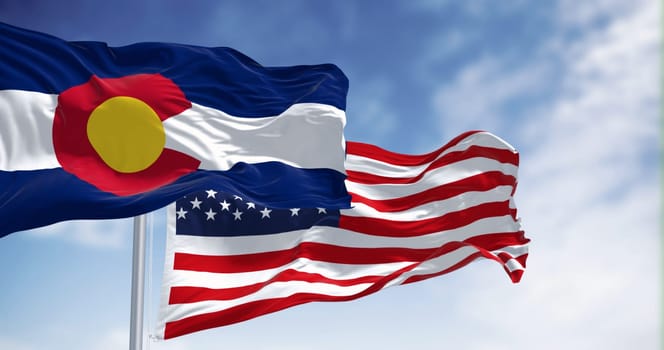 The Colorado state flag waving with the national flag of the United States of America on a clear day. 3D illustration render. Rippled textile