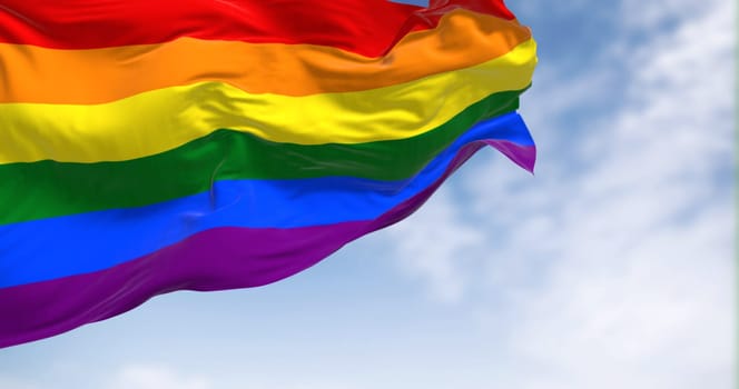 Rainbow flag waving on a clear day. Multicolored flag with stripes in the colors of the rainbow, often used as a symbol of LGBT pride. 3d illustration render. Fluttering fabric