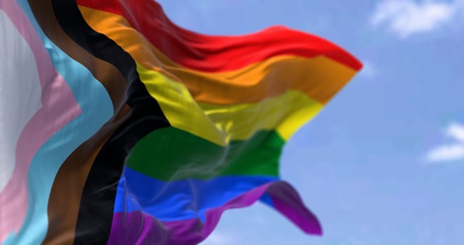 Progress Pride flag waving on a clear day. Black, brown, light blue, pink, and white to the rainbow flag to represent marginalized LGBTQ+ communities. 3d illustration render. Selective focus.