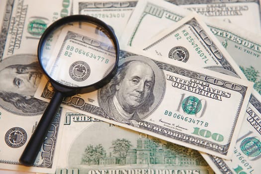 Verifying the authenticity of a hundred dollar bill with an enlarged image of the bill number