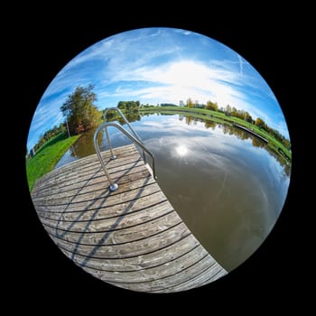 Wooden dock at a lake with sun and trees landscape with fish-eyxe distortion